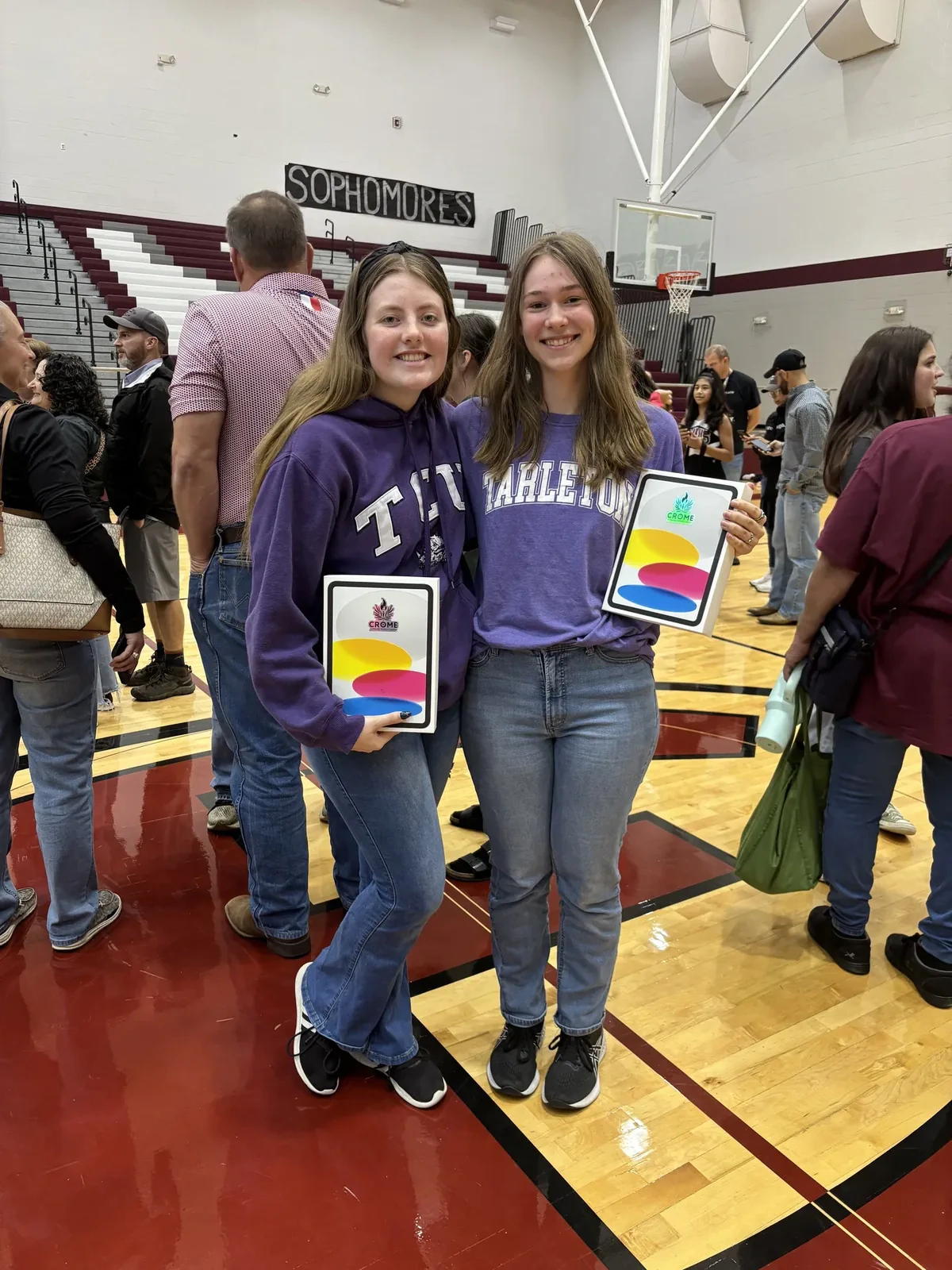 Two students holding CROME tablet prizes at the 2025 Ennis High School senior pep rally